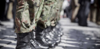 Row of soldiers in black boots and camouflage pants standing in formation