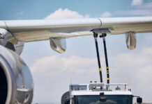 Close-up of an airplane wing being fueled by a ground support truck