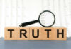 Wooden blocks spelling truth with magnifying glass