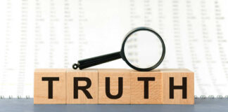 Wooden blocks spelling truth with magnifying glass