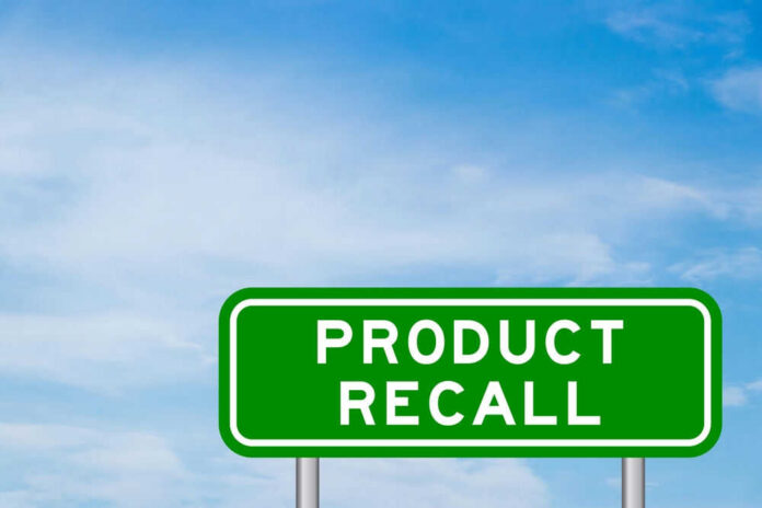 Green sign with product recall text and sky background