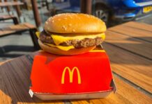A cheeseburger from McDonald's placed on a red box on a wooden table