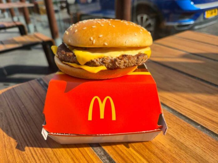 A cheeseburger from McDonald's placed on a red box on a wooden table