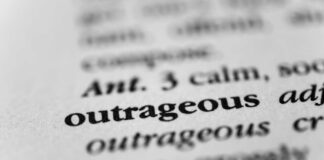 Close-up of a dictionary entry highlighting the word 'outrageous'