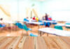 Blurred classroom with students and a wooden foreground.