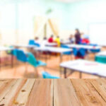 SHOWDOWN Looms Over God in Classrooms Blurred classroom with students and a wooden foreground.