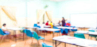 Blurred classroom with students and a wooden foreground.