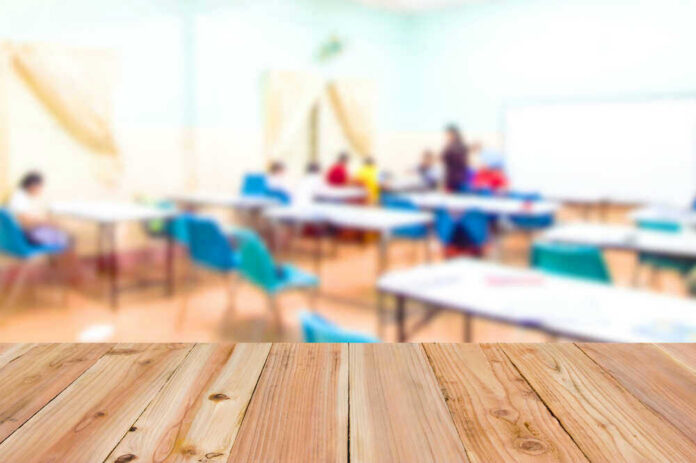 Blurred classroom with students and a wooden foreground.