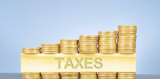 Stacked coins with TAXES on block beneath.