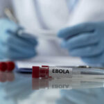 Ebola test tubes on lab table with gloved scientist in background