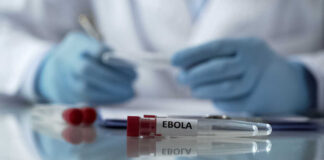 Ebola test tubes on lab table with gloved scientist in background