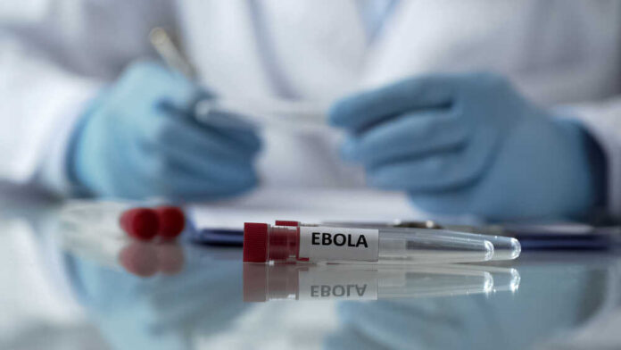 Ebola test tubes on lab table with gloved scientist in background