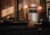 Judge’s Shocking Sex Scandal: Just a Reprimand? Interior of a courtroom with wooden paneling and green desk lamp