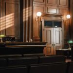 Judge’s Shocking Sex Scandal: Just a Reprimand? Interior of a courtroom with wooden paneling and green desk lamp