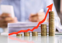 THESE Prices Ignite Economic Alarm Stacked coins with upward red arrow graph in foreground.