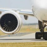 Close-up of an airplane engine and landing gear on a runway