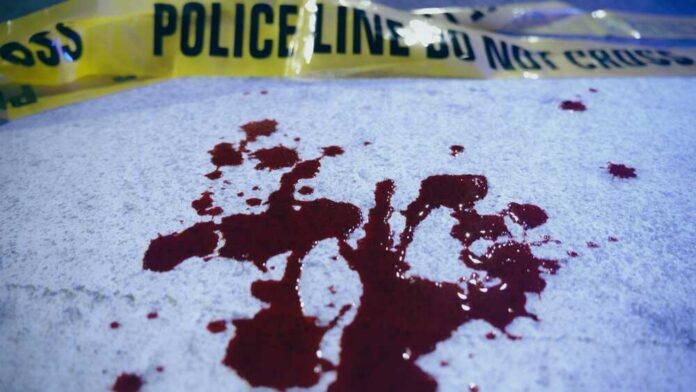 Close-up,Of,Blood,Stains,On,Crosswalk,Asphalt,Near,Yellow,Police Blood stains on a surface with police caution tape in the background