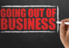 Century-Old Plant Shuts Down! A hand writing 'GOING OUT OF BUSINESS' on a chalkboard