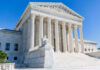 Supreme Court building with columns, fountain, and statue.