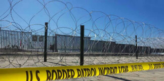 Border patrol tape and barbed wire fence.