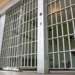 IRS Agent Kills 2, Land In Prison Empty prison cell with metal bars and toilet.