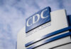 CDC building sign against a cloudy sky.