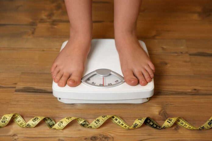 Overweight,Girl,Using,Scales,Near,Measuring,Tape,On,Wooden,Floor,