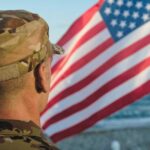Trump Reveals Secret Military Mission Soldier in uniform standing in front of an American flag by the ocean