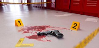 Handgun on a blood-stained floor with evidence markers in a locker room