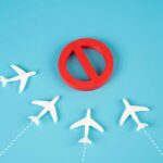 A red prohibition sign surrounded by white airplane models on a blue background