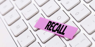 A pink sticky note with the word 'RECALL' placed on a white keyboard