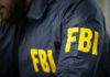Standoff Ends, FBI Saves 10 Hostages FBI agent in navy blue jacket.
