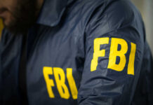 Standoff Ends, FBI Saves 10 Hostages FBI agent in navy blue jacket.