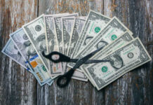 Patriotic Price Cut — Or Power Play? Scissors placed on a spread of various U.S. dollar bills