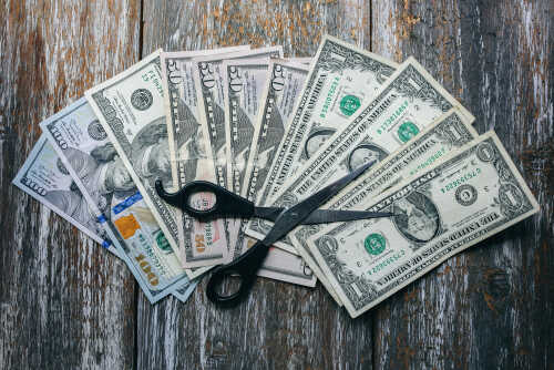 Dollar,Banknotes,With,Scissors,Lying,On,The,Natural,Vintage,Background. Scissors placed on a spread of various U.S. dollar bills