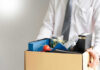 100,000 Jobs Bombshell – 50,000 Already Gone Person holding a box of personal office items.