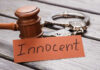 Convicted Killer Flip-Flops: Now ‘Innocent’ A wooden gavel next to handcuffs and a card that says 'Innocent'