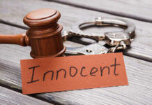 A wooden gavel next to handcuffs and a card that says 'Innocent'