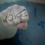 Woke Makeover Backfires — CEO Out Fist with Woke written on fingers.