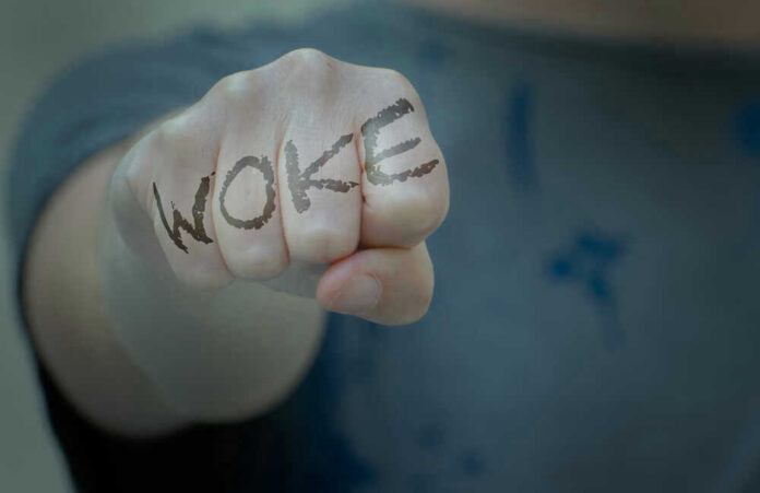 shutterstock_2002018643 Fist with Woke written on fingers.