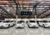 White Tesla cars displayed in showroom with Tesla sign.