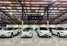 Blinding Wipers, Runaway Mustangs? White Tesla cars displayed in showroom with Tesla sign.