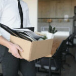 AI Ax Falls at Massive Global Employer Person carrying box of office supplies in workspace.