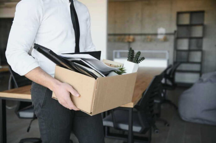 shutterstock_2290780995 Person carrying box of office supplies in workspace.