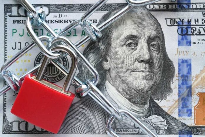 Lock,And,Chain,On,Cash,,Money,Restrictions,,Frozen,Assets,,Business A red padlock and chain over a hundred dollar bill featuring Benjamin Franklin