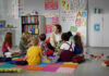 Children sitting on the floor around a teacher.