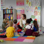 Children sitting on the floor around a teacher.
