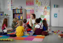 Children sitting on the floor around a teacher.