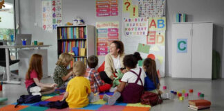 Children sitting on the floor around a teacher.