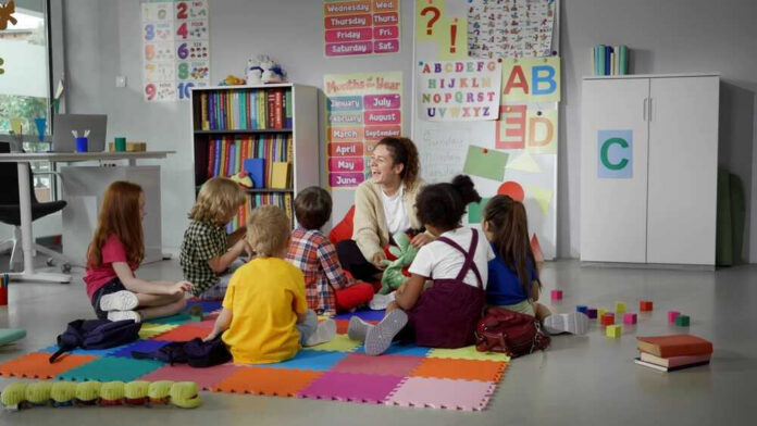 Children sitting on the floor around a teacher.